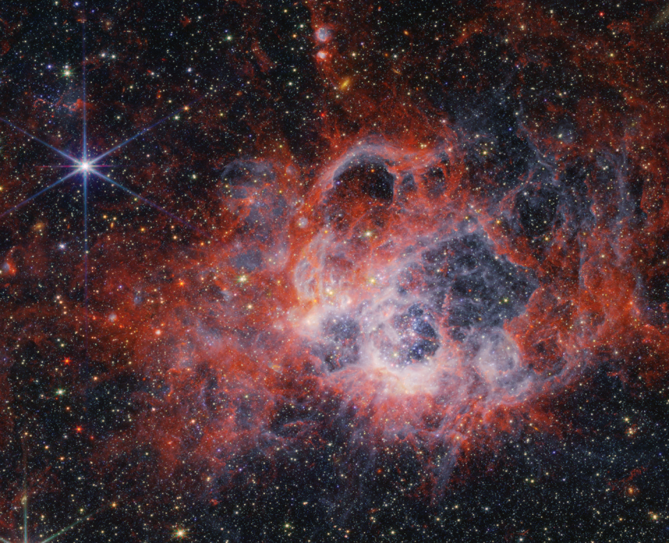 Clouds of red, pink and white gas and dust accent this starscape.