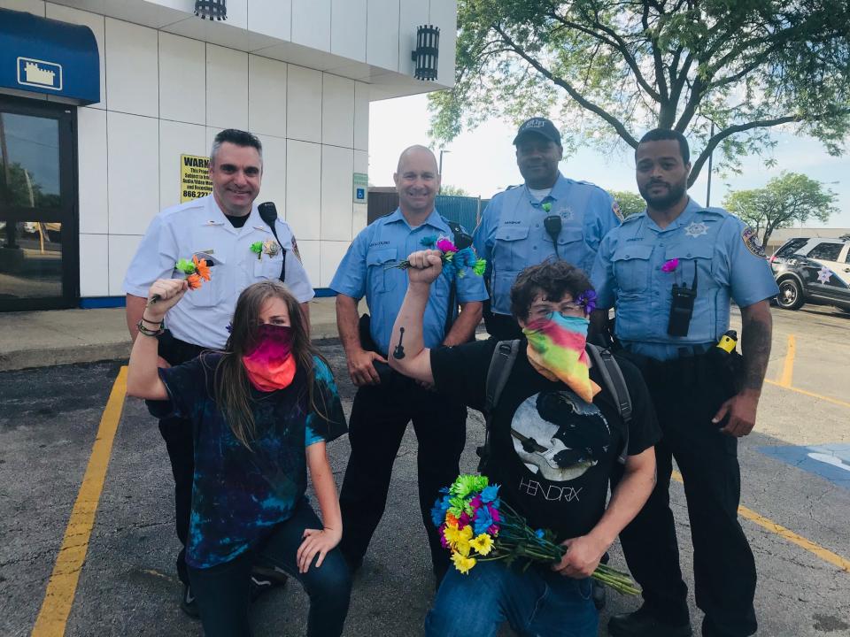 At the June Black Lives Matter demonstration, Edgar Ascencio of Joliet and Olivia Walker of Minooka pose for photographs with the group of Joliet police officers who were appreciative of their kindness and friendly tone during the protest. Image via John Ferak/Patch