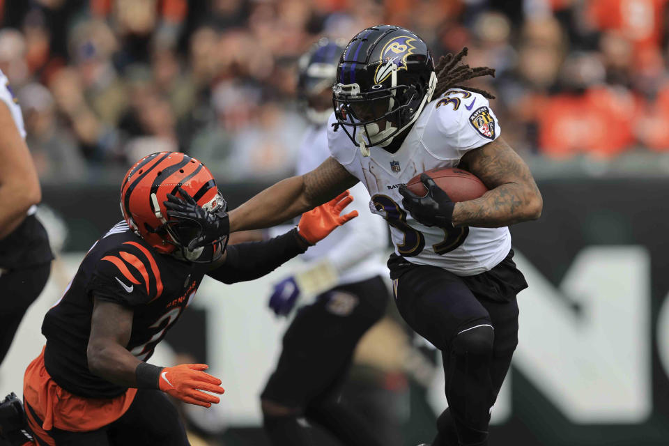 Baltimore Ravens' Devonta Freeman (33) is tackled by Cincinnati Bengals' Mike Hilton (21) during the first half of an NFL football game, Sunday, Dec. 26, 2021, in Cincinnati. (AP Photo/Aaron Doster)