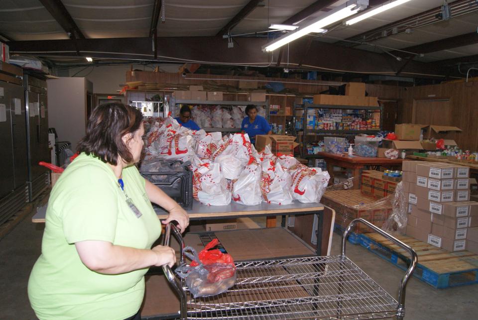 Volunteer Georgia Naquin, 48, of Houma pushes a cart and gathers supplies for at the Terrebonne Churches United Food Bank in Houma as Veda Bailey, 60, and Lauren Owens, 28, load bags in the background Wednesday, June 1, 2022.
