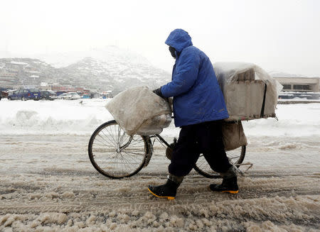 An Afghan man pushes his bicycle on a snowy day in Kabul, Afghanistan February 5, 2017. REUTERS/Omar Sobhani