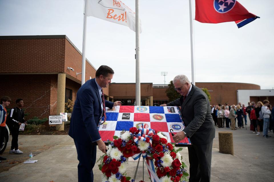 Powell High School principal Chad Smith and Jimmie A. "Rusty" Smith Jr. unveil a monument to 13 former students killed in action from WWII to the Vietnam War.