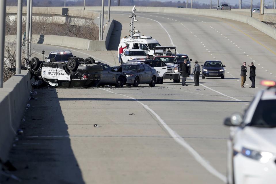 Police work at the scene along Interstate-95 North near the Philadelphia International Airport following a crash during a multi-state police chase Wednesday, Jan. 9, 2019, in Philadelphia. A Wilmington, Del., police vehicle, at left, flipped in the chase. Police launched a manhunt in South Philadelphia for a murder suspect who led police on a chase along Interstate 95, triggering a crash that left three officers injured, and then fled on foot after crashing into a SEPTA bus at Broad and Oregon Streets. (David Maialetti/The Philadelphia Inquirer via AP)