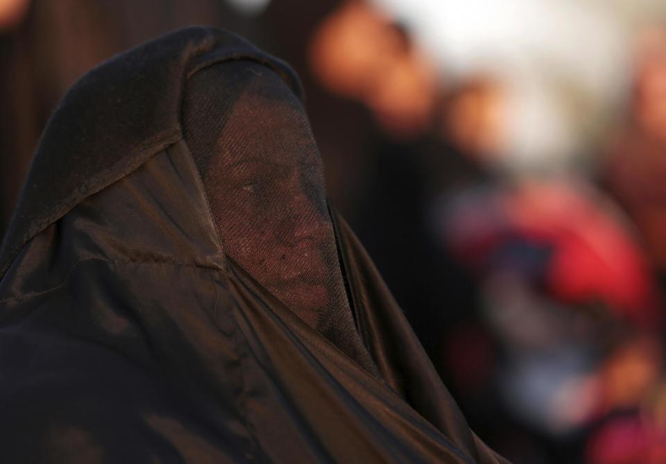 A Bahraini woman stops to rest during a pro-democracy march near Saar, west of the capital Manama, Bahrain, Saturday, Feb. 15, 2014. Tens of thousands of protesters marched down a divided four-lane highway calling for the long-serving prime minister, Sheik Khalifa bin Salman Al Khalifa, to step down and for democracy in the Gulf island kingdom. (AP Photo/Hasan Jamali)