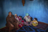 In this in Wednesday, March 25, 2020 photo, Kaddour El Miny, left, sits with his family in a room in a housing complex in Sale, near Rabat, Morocco. Hundreds of people live in crowded rooms in this Moroccan housing complex with no running water and no income left because of the coronavirus lockdown measures. However volunteers come to help clean as the government tries to protect the population from virus while not punishing the poor. (AP Photo/Mosa'ab Elshamy)