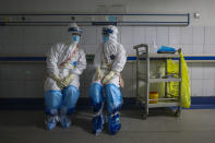 In this Sunday, Feb. 16, 2020, photo, medical workers wearing full protective suits chat to each other at a hospital in Wuhan in central China's Hubei province. Chinese authorities on Monday reported a slight upturn in new virus cases and hundred more deaths for a total of thousands since the outbreak began two months ago. (Chinatopix via AP)