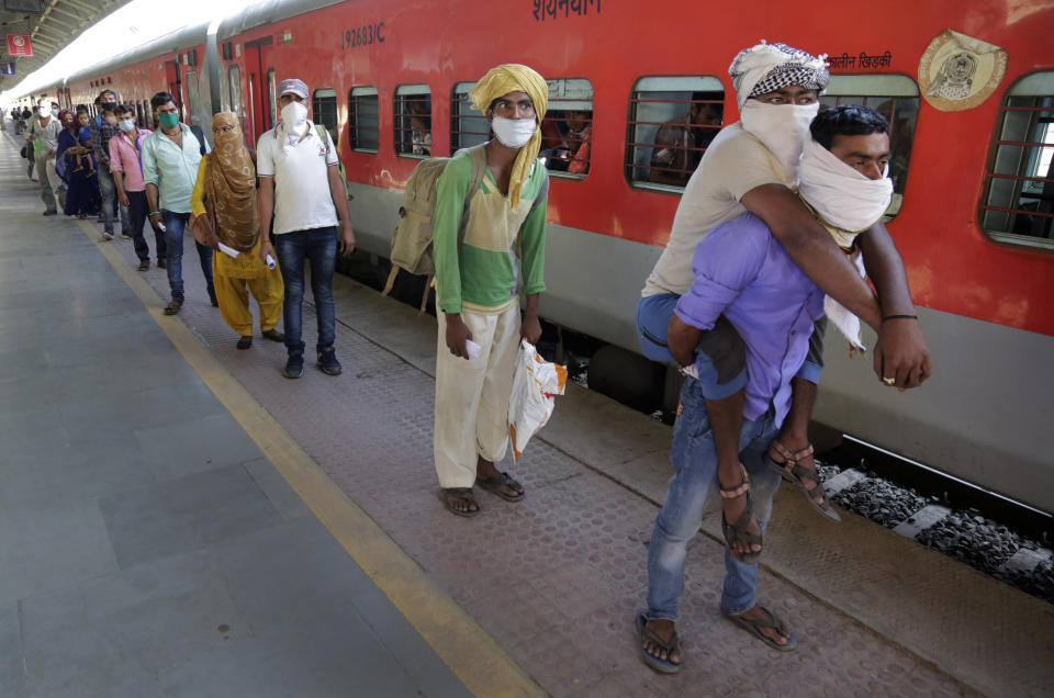 Hira Ali carries his physically disabled brother, Muslim Ali, on his back as they wait to board a special train to return to Agra in Uttar Pradesh state, during a nationwide lockdown to curb the spread of new coronavirus, at a railway station in Ahmedabad, in the western Indian state of Gujarat, on Saturday, May 2, 2020. Tens of thousands of impoverished migrant workers are on the move across India, walking on highways and railway tracks or riding trucks, buses and crowded trains in blazing heat. They say they have been forced to leave cities and towns where they had toiled for years building homes and roads after they were abandoned by their employers due to a lockdown to stop the virus from spreading. (AP Photo/Ajit Solanki)