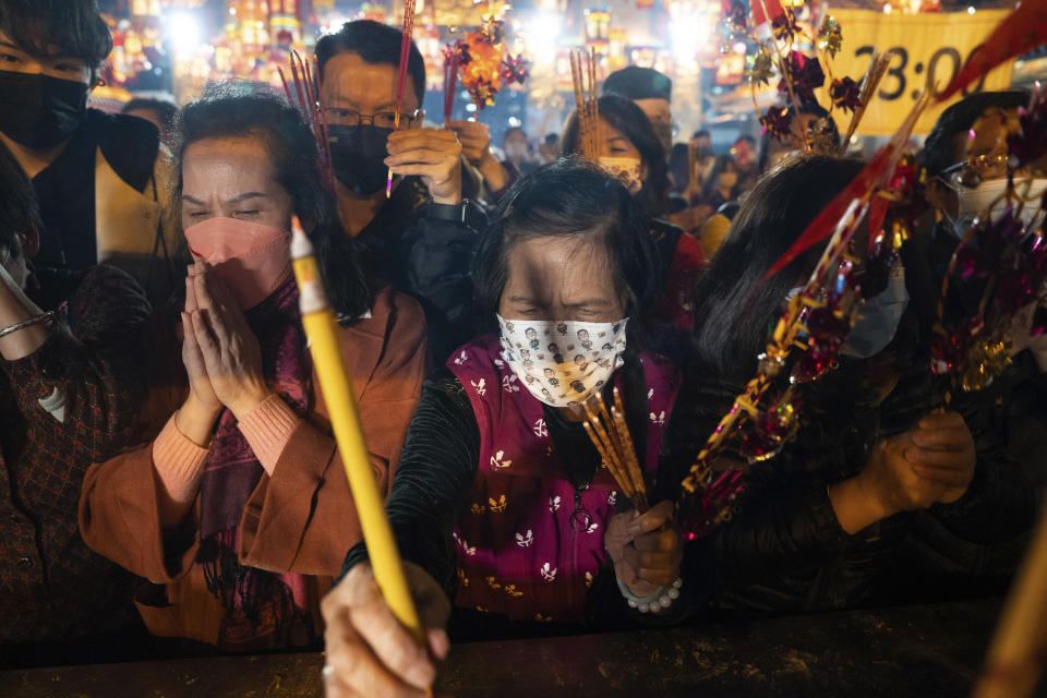 Fieles con mascarillas preden sus primeras varitas de incienso mientras rezan en el templo Wong Tai Sin de Hong Kong, el sábado 21 de enero de 2023, para celebrar el inicio del Año Nuevo Lunar. (AP Foto/Bertha Wang)