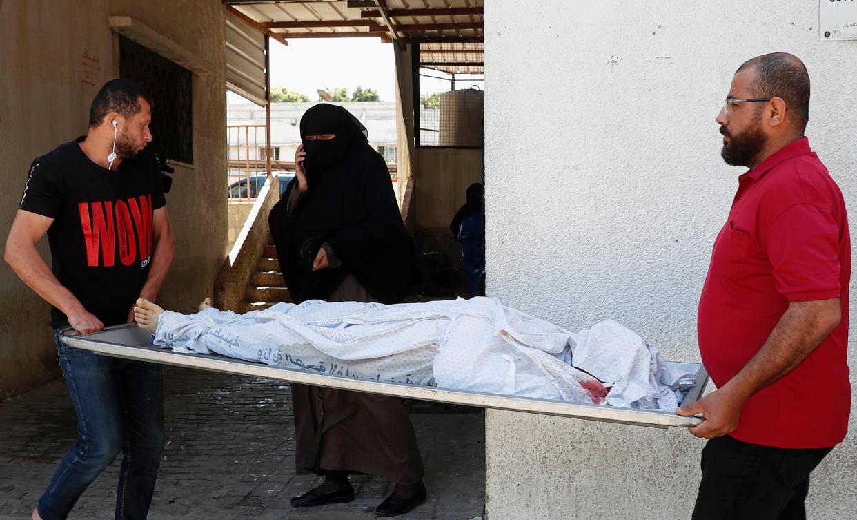 Mourners carry the body of Zaid Telbani, who was killed in Israeli airstrikes on his family apartment building, at Dar Al-Shifa Hospital in Gaza City, Wednesday, May 12, 2021. (AP Photo/Adel Hana)