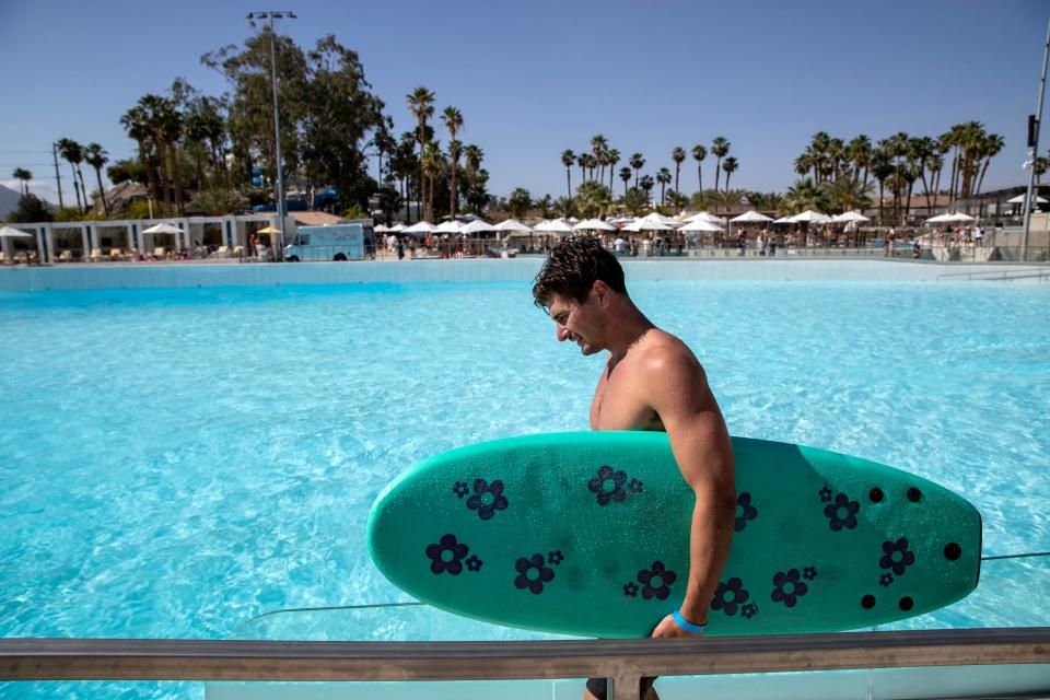 Surfer Garrett Abddulla of Dana Point carries a surfboard back to the top of the wave pool during Goldenvoice Surf Club in Palm Springs, Calif., on Saturday, April 13, 2024.