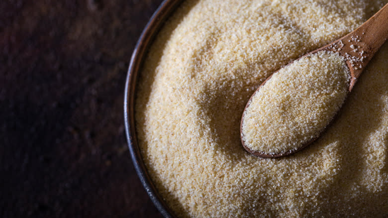 A bowl of semolina flour with wooden spoon