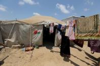 A Palestinian woman collects laundry near the ruins of her house, that witnesses said was destroyed by Israeli shelling during a 50-day war last summer, in Khan Younis in the southern Gaza Strip July 2, 2015. REUTERS/Ibraheem Abu Mustafa