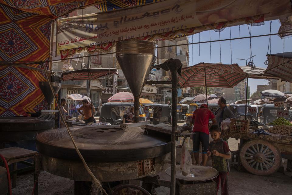 This May 9, 2020 photo, shows the Ramadan sweets shop where 28-year-old football defender Mahrous Mahmoud works at a market, in Manfalut, a town 350 kilometers (230 miles) south of Cairo, in the province of Assiut, Egypt. Mahmoud should be on the field at this time of year playing as a defender for Beni Suef, a club in Egypt's second division. But like millions in the Arab world's most populous country, he has been hit hard by the coronavirus pandemic. (AP Photo/Nariman El-Mofty)