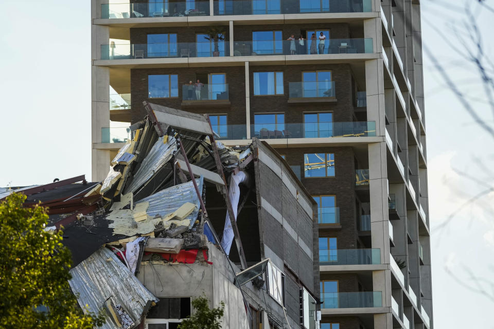 People look at the rubble of a building that partially collapsed killing one person in Antwerp, Belgium, Friday, June 18, 2021. Local police reported that one person was killed and several were injured after an under construction building and its scaffolding collapsed in a new apartment blocks area. (AP Photo/Francisco Seco)