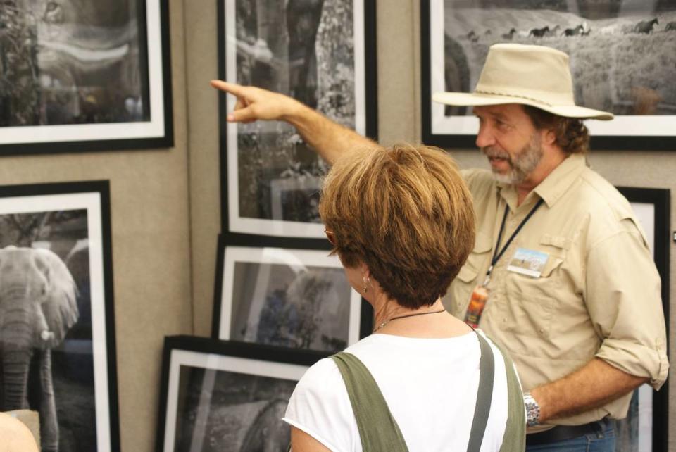 Photgrapher David Julian of Red Feather Lakes, Colo., speaks to a visitor at Art on the Square in downtown Belleville Saturday.