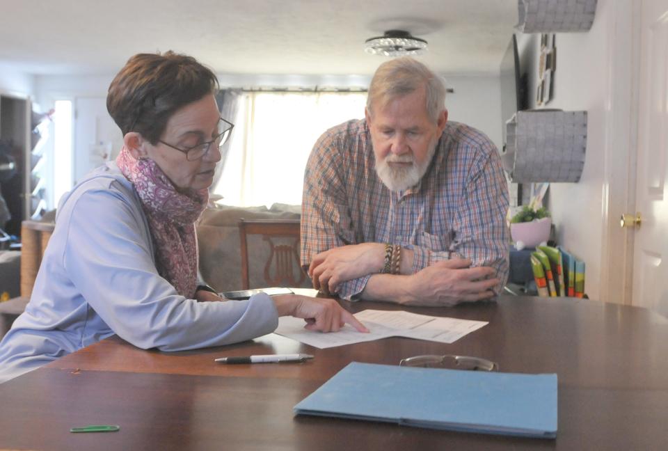 Deborah Davis, a volunteer with Elder Services of Cape Cod and the Islands Money Management Program, left, goes over a client's monthly bank statement with him on Wednesday in East Falmouth. In the program, trained volunteers meet with individuals in their homes to help them pay monthly bills and manage their money wisely. Volunteers also help elders avoid becoming victims of fraud, scams or financial exploitation.