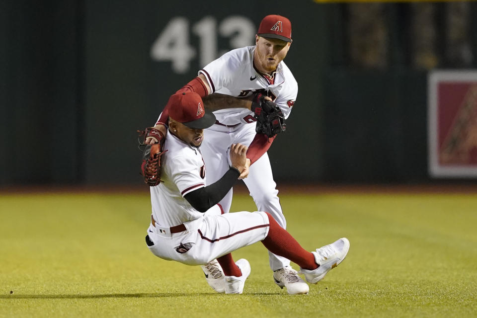 Arizona Diamondbacks' Pavin Smith catches a fly-out hit by Los Angeles Dodgers' Trea Turner as he collides with teammate Ketel Marte (4) during the fifth inning of a baseball game, Monday, April 25, 2022, in Phoenix. (AP Photo/Matt York)