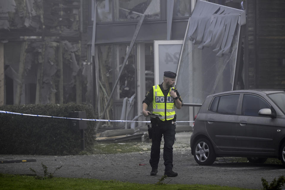 A police officer stands on the site of a powerful explosion that occurred early Thursday morning Sept. 28, 2023, in a housing area in Storvreta outside Uppsala, Sweden. A 25-year-old woman died in the blast. (Anders Wiklund/TT News Agency via AP)
