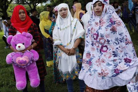 A Muslim woman hold a doll as she attend Eid al-Fitr prayers to mark the end of the holy fasting month of Ramadan in Taipei , Taiwan June 25, 2017. REUTERS/Tyrone Siu