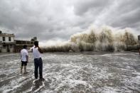 People watch waves hit the shores as Typhoon Usagi approaches in Shantou, Guangdong province, September 22, 2013. China's National Meteorological Center issued its highest alert, warning that Usagi would bring gales and downpours to southern coastal areas, according to the official Xinhua news agency. Major Chinese airlines cancelled flights to cities in the southern provinces of Guangdong and Fujian while shipping was suspended between the Chinese mainland and Taiwan, Xinhua also reported. REUTERS/Stringer (CHINA - Tags: ENVIRONMENT DISASTER) CHINA OUT. NO COMMERCIAL OR EDITORIAL SALES IN CHINA