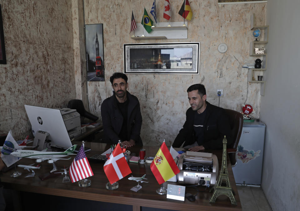 Owners of the Yaran Travel, sit in their office where many would-be migrants come for help, in Ranya, a town in the Kurdish-run region of Iraq, Tuesday, Nov. 30, 2021. People ask travel agents to connect them with smugglers in Turkey and Europe, often relatives and friends. (AP Photo/Khalid Mohammed)