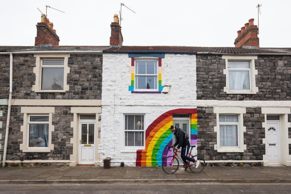 CARDIFF, WALES - APRIL 02: A man rides his bike passed a terraced house painted with a rainbow in support of the National Health Service (NHS) on Gwendoline Street in Splott on April 2, 2020, in Cardiff, Wales. The Coronavirus (COVID-19) pandemic has spread to many countries across the world, claiming over 45,000 lives and infecting hundreds of thousands more. (Photo by Matthew Horwood/Getty Images)