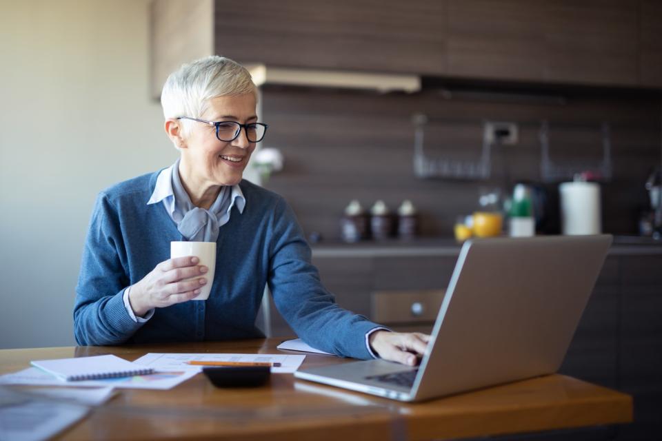 Person at kitchen table, looking at laptop.