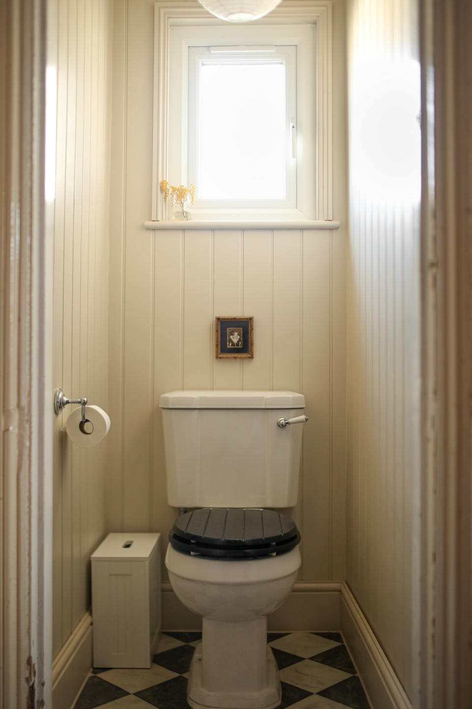 A modern bathroom with a cream wood panelled walls and toilet with wooden toilet seat