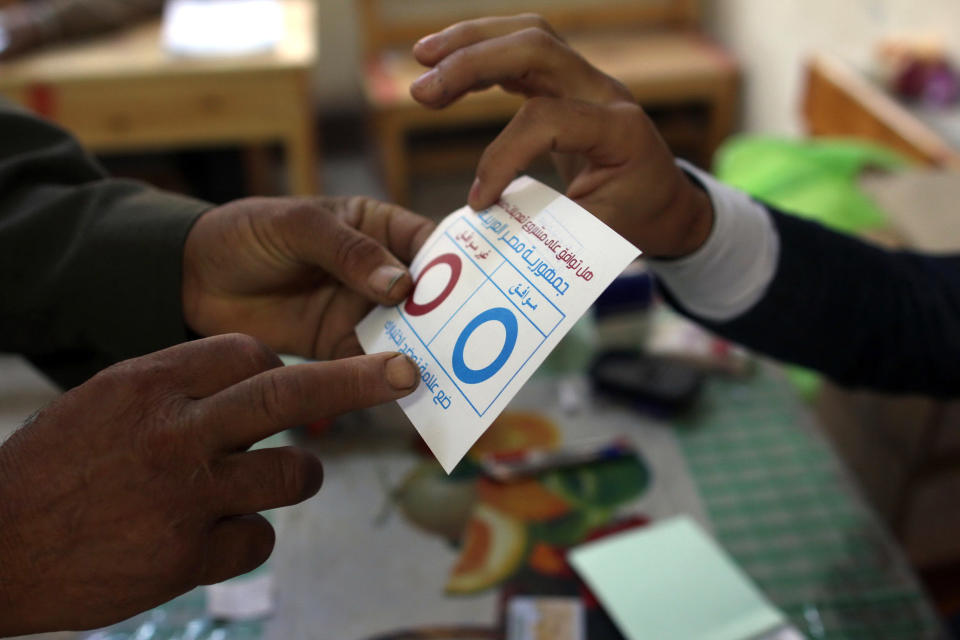 A judge shows a villager a ballot for the constitutional referendum inside a polling station in Dalga village of Minya, Egypt, Wednesday, Jan. 15, 2014. Through violence or intimidation, Islamists in villages like this one used violence or intimidation to stop Christians from voting "no" to a 2012 constitution that had paved the way for the creation of an Islamic state. This time around, no one is stopping the Christians and they are voting "yes" on a new charter that criminalizes discrimination and instructs the next legislature to ease restrictions on building churches. (AP Photo/Roger Anis, El Shorouk Newspaper) EGYPT OUT