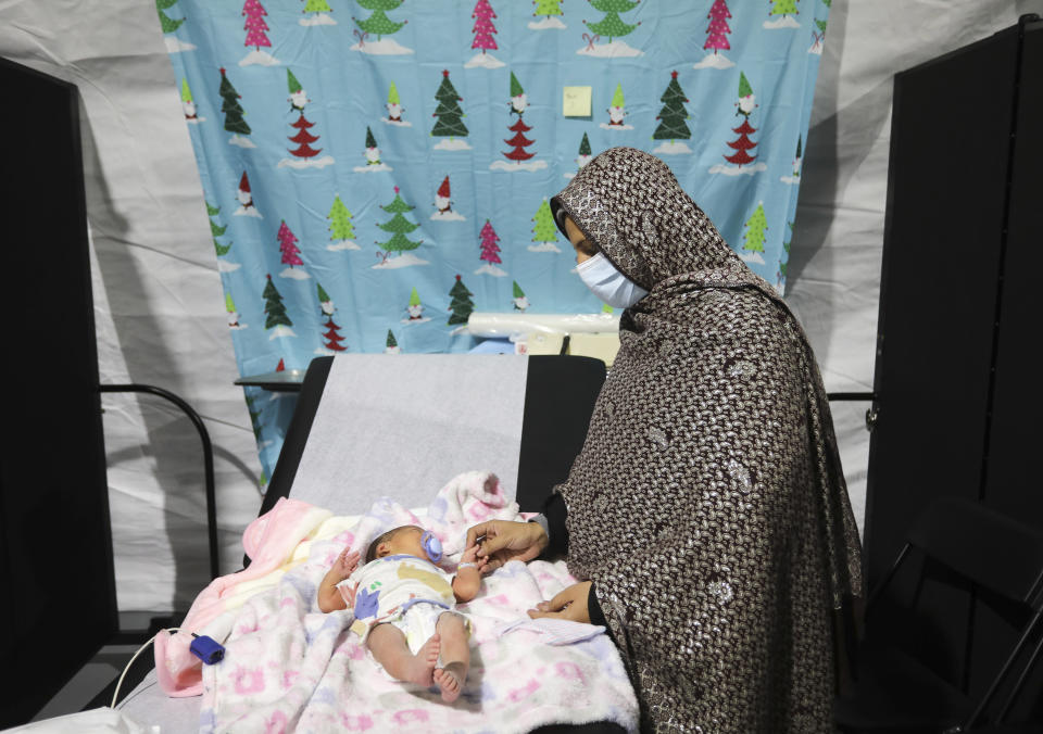 An Afghan refugee woman caresses her 9-day old child inside the pediatric ward of a medical treatment facility at Joint Base McGuire-Dix- Lakehurst in Trenton, N.J., Thursday, Dec. 2, 2021. (Barbara Davidson/Pool via AP)