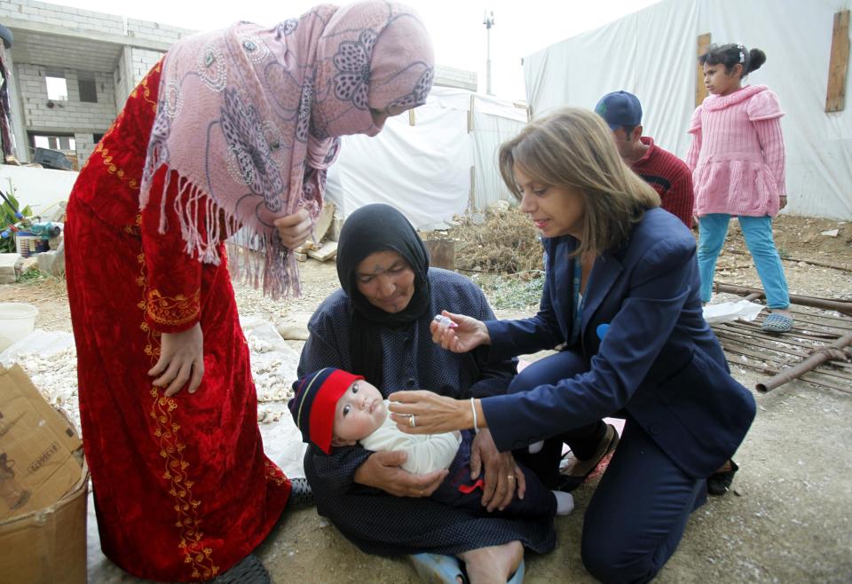 UNICEF's Laurini administers a polio vaccine to a baby at a Syrian refugee camp in the Bekaa Valley