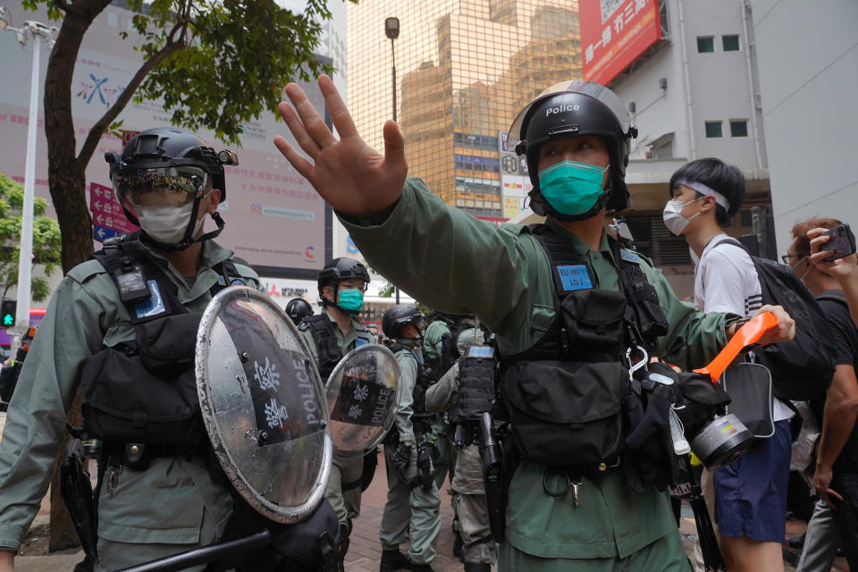 Riot police form a line and issue warnings as they plan to clear away people gathered in the Causeway Bay district of Hong Kong Wednesday, May 27, 2020. Hong Kong police massed outside the legislature complex Wednesday, ahead of debate on a bill that would criminalize abuse of the Chinese national anthem in the semi-autonomous city. (AP Photo/Vincent Yu)