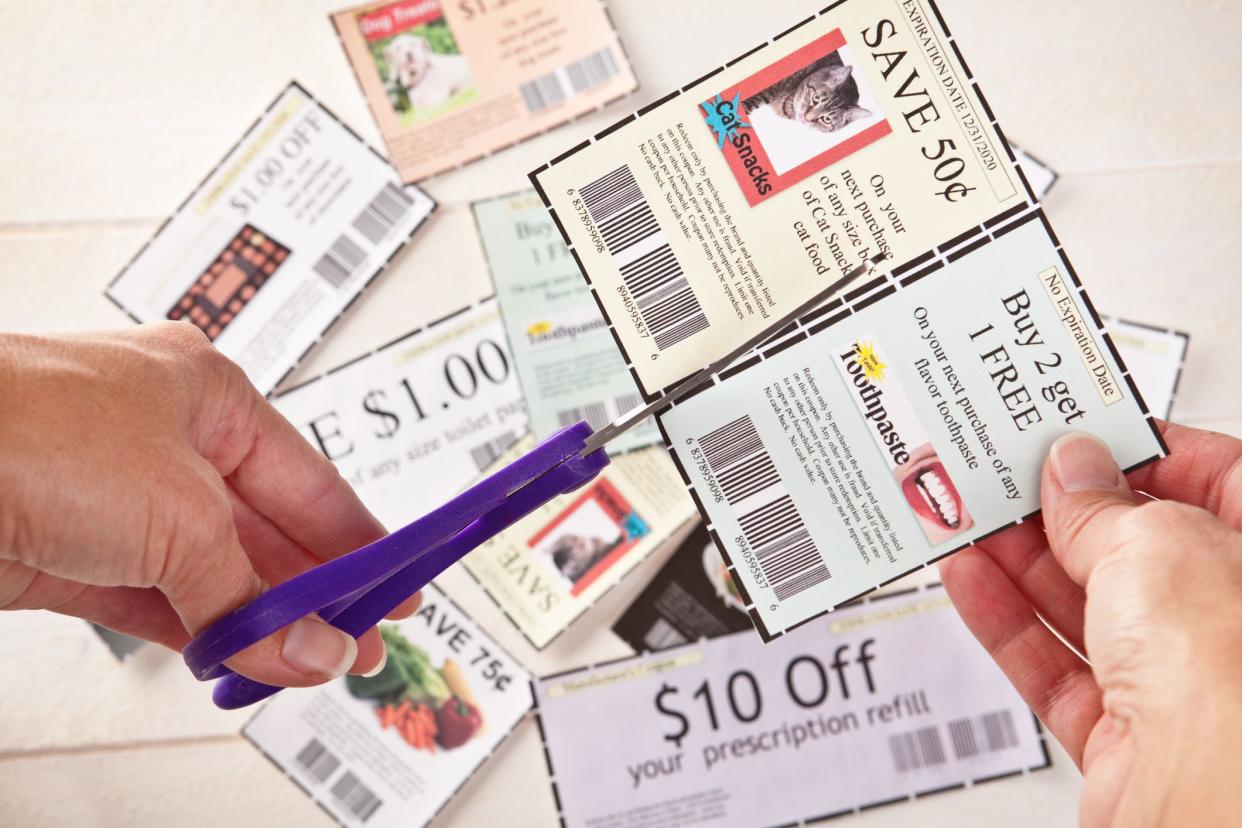 A womans hands clipping coupons with scissors.  (coupons were created by photographer using own photos)