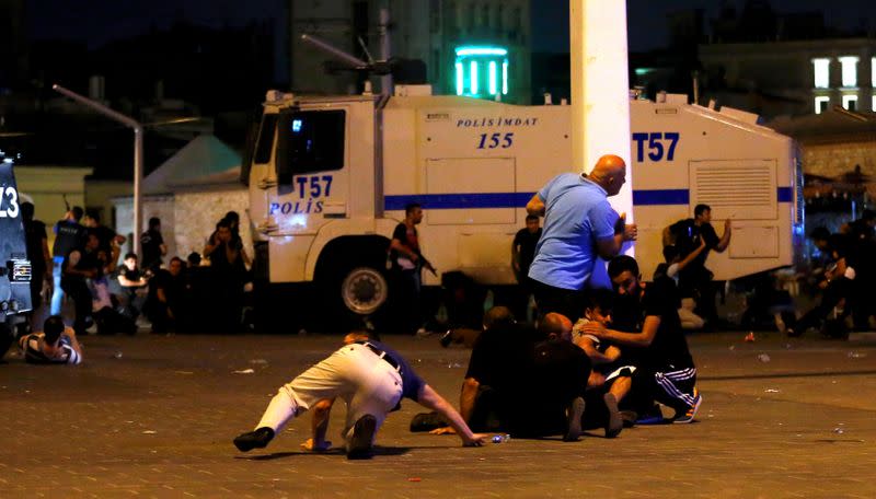 FILE PHOTO: People take cover near policemen as gunfire are heard during an attempted coup in Istanbul's Taksim Square