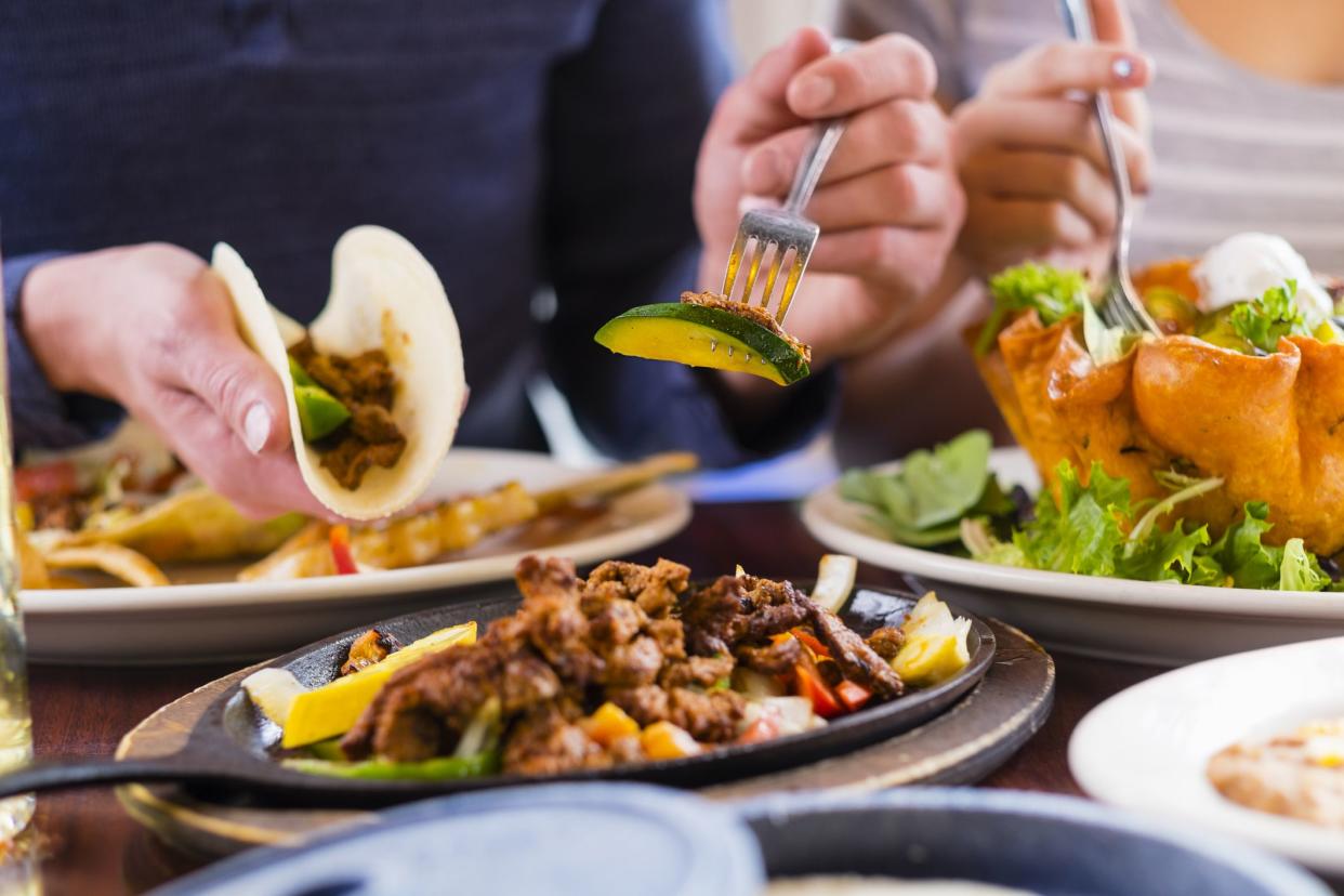 A young man eating a fajita at a restaurant table.