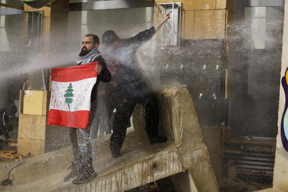 Riot police spray anti-government protesters with water cannons during a protest against a parliament session preparing a vote of confidence for the new government in downtown Beirut, Lebanon, Tuesday, Feb. 11, 2020. (AP Photo/Bilal Hussein)