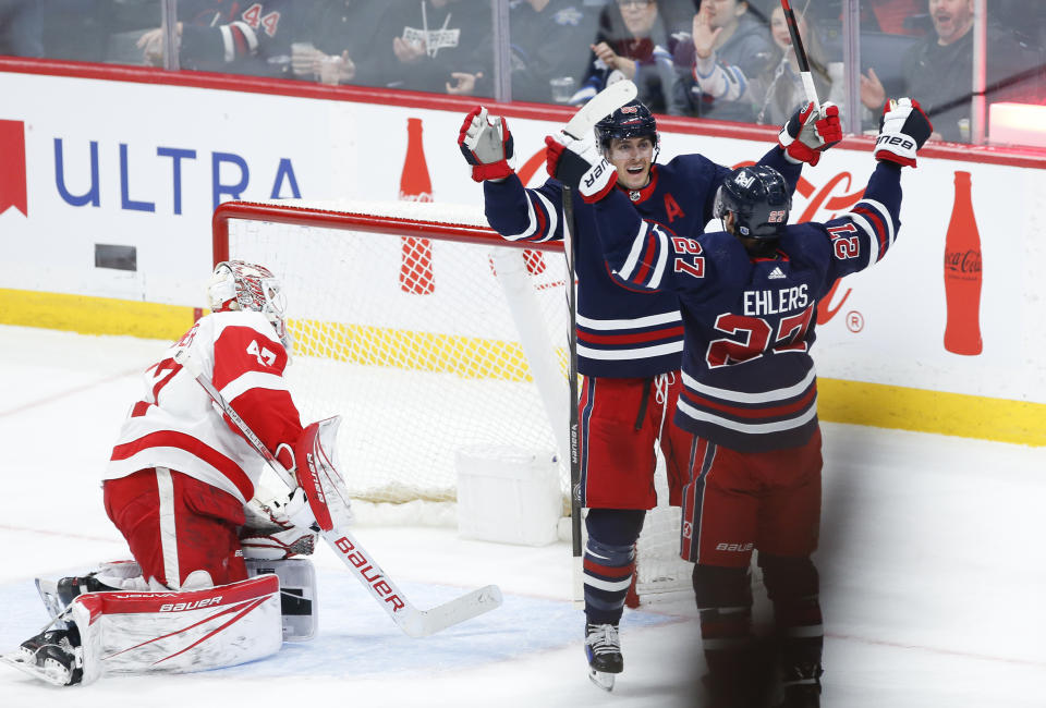 Winnipeg Jets' Mark Scheifele (55) and Nikolaj Ehlers (27) celebrate Ehlers' goal against Detroit Red Wings goaltender James Reimer (47) during the second period of an NHL hockey game Wednesday, Dec. 20, 2023, in Winnipeg, Manitoba. (John Woods/The Canadian Press via AP)