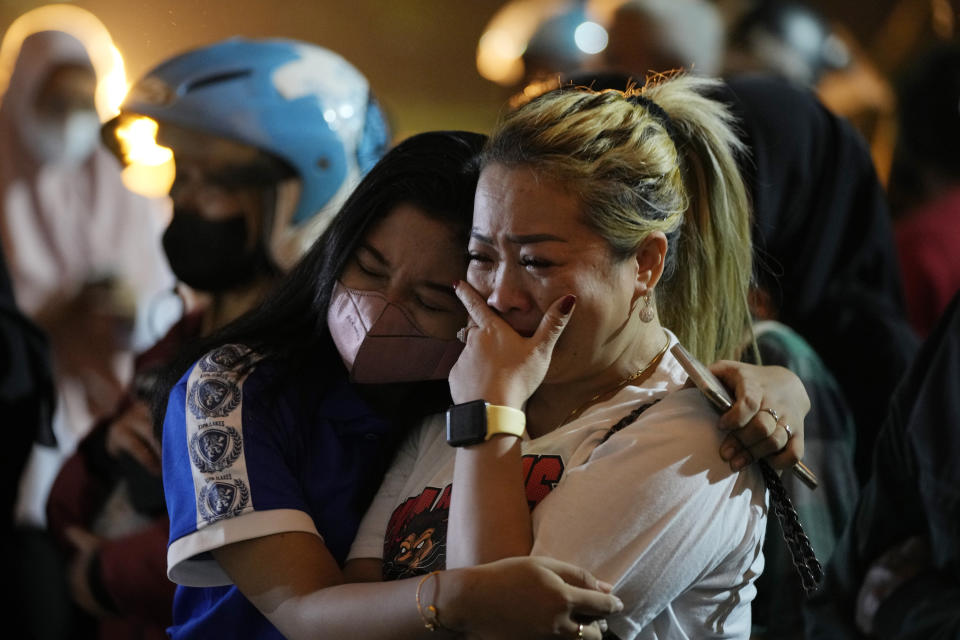 A woman weeps as she offers prayers in front of gate 13 at the Kanjuruhan Stadium in Malang, Indonesia, Tuesday, Oct. 4, 2022. Police said Tuesday that the gates at the soccer stadium where police fired tear gas and set off a deadly crush were too small and could only accommodate two at a time when hundreds were trying to escape. (AP Photo/Achmad Ibrahim)