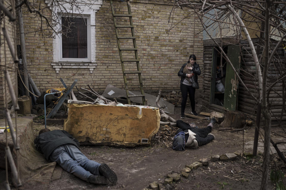 ARCHIVO - Ira Gavriluk sostiene a su gato mientras camina junto a los cuerpos de su esposo, su hermano y otro hombre que fueron asesinados afuera de su casa, el lunes 4 de abril de 2022, en Bucha, Ucrania. (AP Foto/Felipe Dana, archivo)