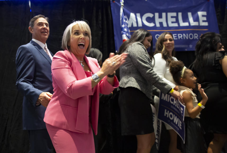 Michelle Lujan Grisham claps in front of a sign that reads: Michelle for Governor.