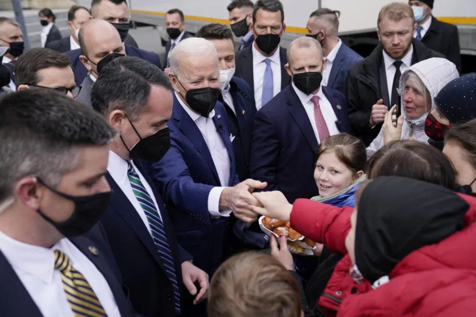 biden shakes hands with person as crowd gathers around him