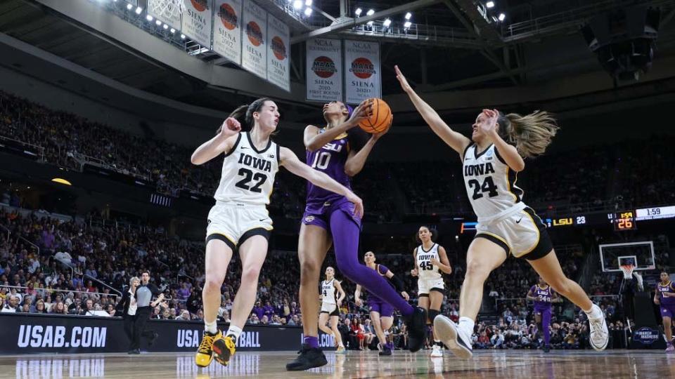  Angel Reese #10 of the LSU Tigers shoots the ball over Caitlin Clark #22 and Gabbie Marshall #24 of the Iowa Hawkeyesduring the first half in the Elite 8 round of the NCAA Women's Basketball Tournament at MVP Arena on April 01, 2024 . 