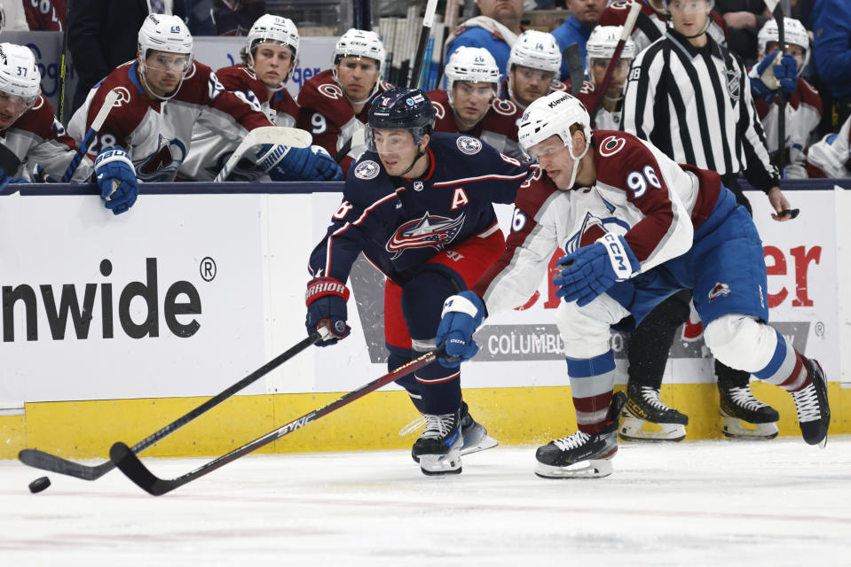 Columbus Blue Jackets defenseman Zach Werenski, left, reaches for the puck in front of Colorado Avalanche forward Mikko Rantanen (96) during the first period of an NHL hockey game in Columbus, Ohio, Monday, April 1, 2024. (AP Photo/Paul Vernon)