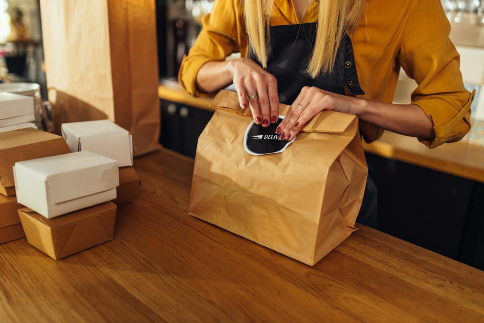 A person at the counter sealing a takeout bag