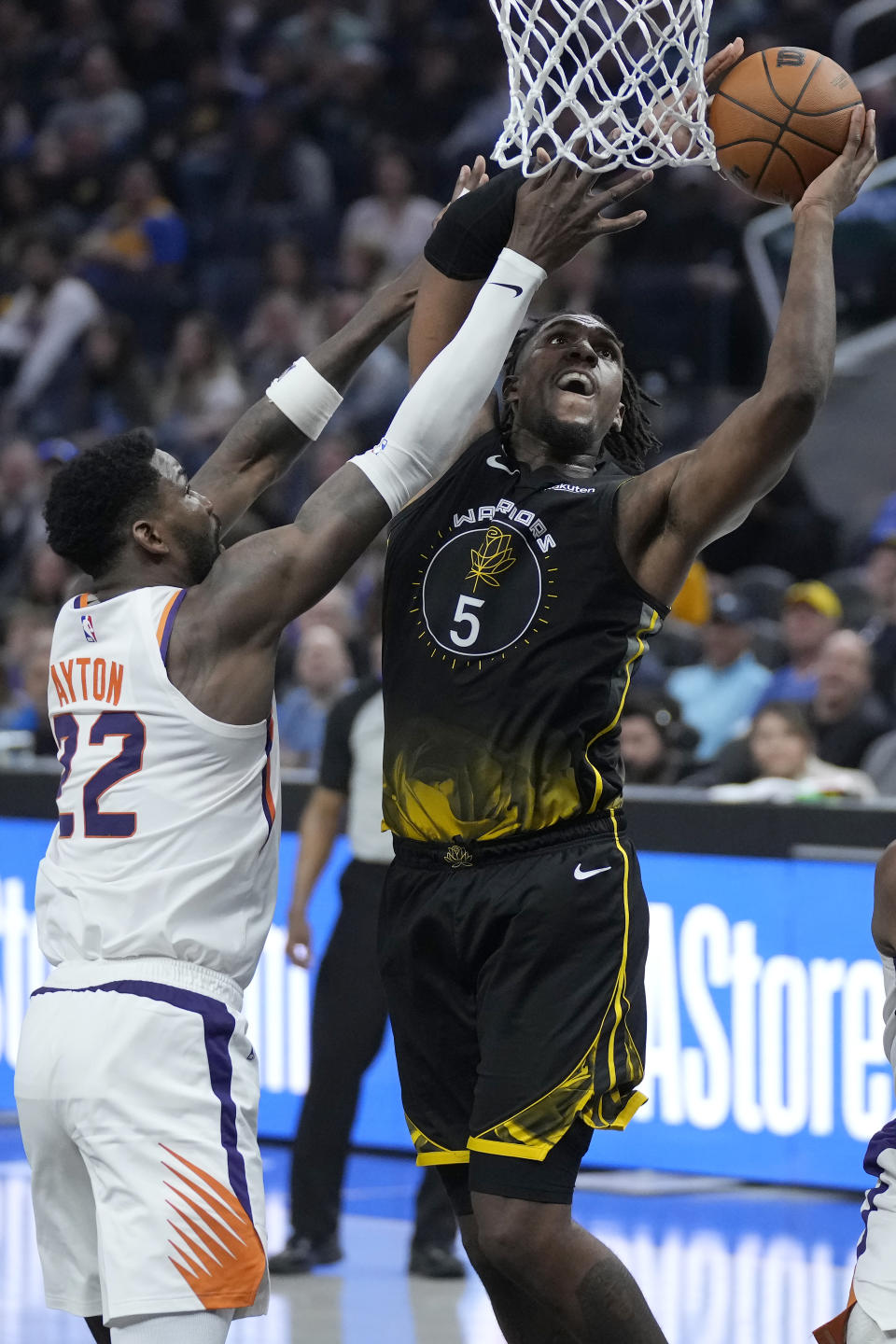 Golden State Warriors forward Kevon Looney (5) scores against Phoenix Suns center Deandre Ayton (22) during the first half of an NBA basketball game in San Francisco, Monday, March 13, 2023. (AP Photo/Jeff Chiu)