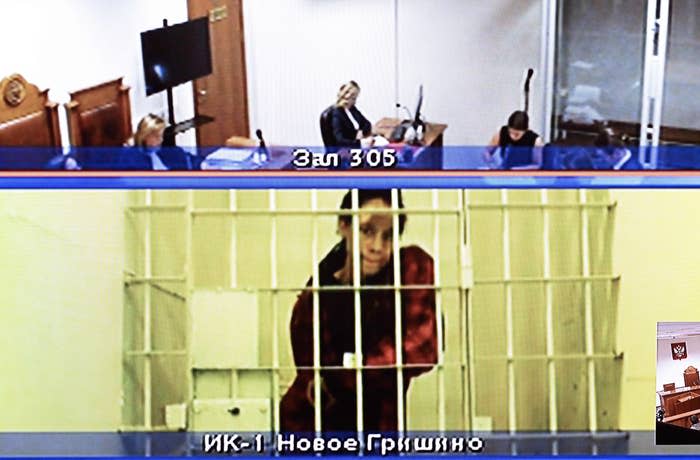 Person in a glass box in court, text on screen indicating location as "Zal 305" and "VKK-1 Novoe Grishino."