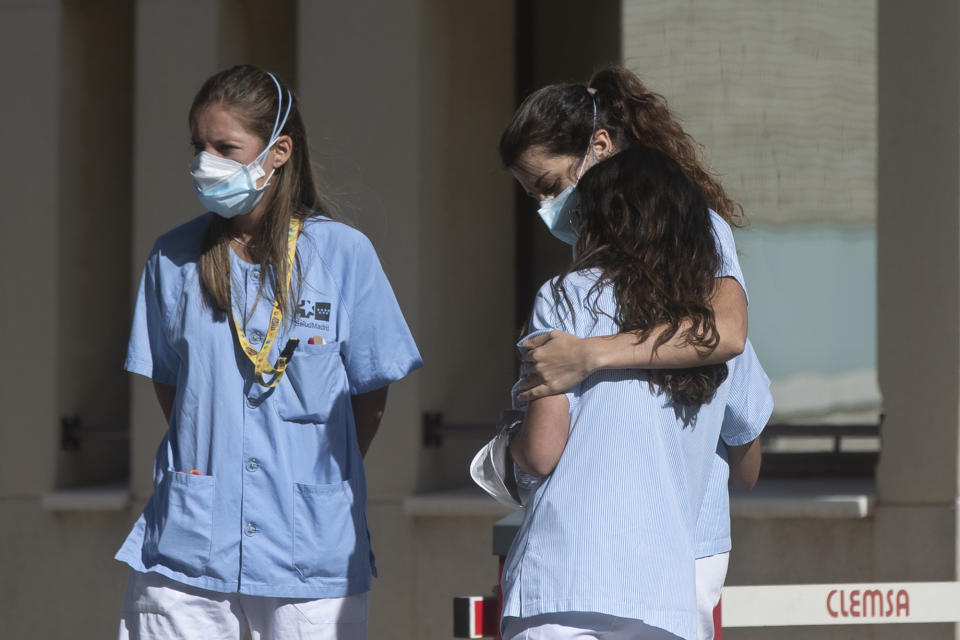 A health worker hugs her colleague during a break outside hospital in Madrid, Spain, Monday, Oct. 5, 2020. Madrid has been the source of Europe’s most worrying surge of infections in the ongoing second wave of the pandemic. (AP Photo/Paul White)