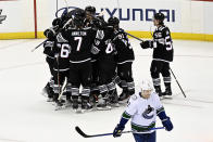 The New Jersey Devils surround Jesper Bratt after his winning goal as Vancouver Canucks defenseman Luke Schenn (2) skates off during the overtime period of an NHL hockey game Monday, Feb. 6, 2023, in Newark, N.J. (AP Photo/Bill Kostroun)