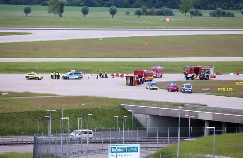 Police and firefighters stand on a runway access road at Franz-Josef-Strauss Airport around climate activists who have stuck themselves there. Climate protection activists paralysed Munich Airport early 18 May. The activists had reached the inner area of the airport grounds. According to their own statements, members of the 'Last Generation' activism group had planned to enter the airport grounds in order to block at least one of the two runways. Karl-Josef Hildenbrand/dpa