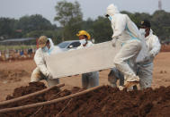 Workers in protective gear carry a coffin of a COVID-19 victim for burial at the special section of the Pedurenan cemetery designated to accommodate the surge in deaths during the coronavirus outbreak in Bekasi, West Java, Indonesia,, Friday, July 30, 2021.(AP Photo/Achmad Ibrahim)